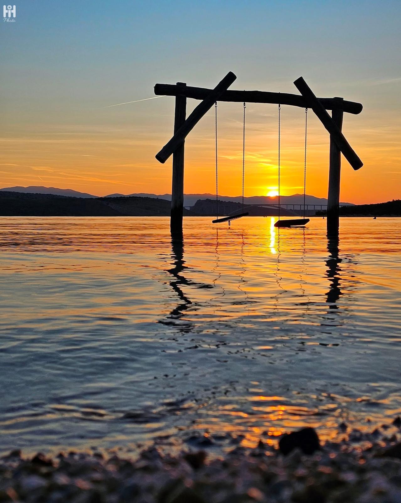 Wooden swings in the sea at sunset